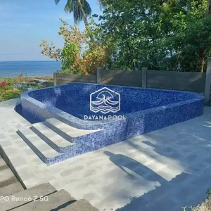 kolalm renang semi overflow dengan keramik biru di tepi pantai buatan dayanapool